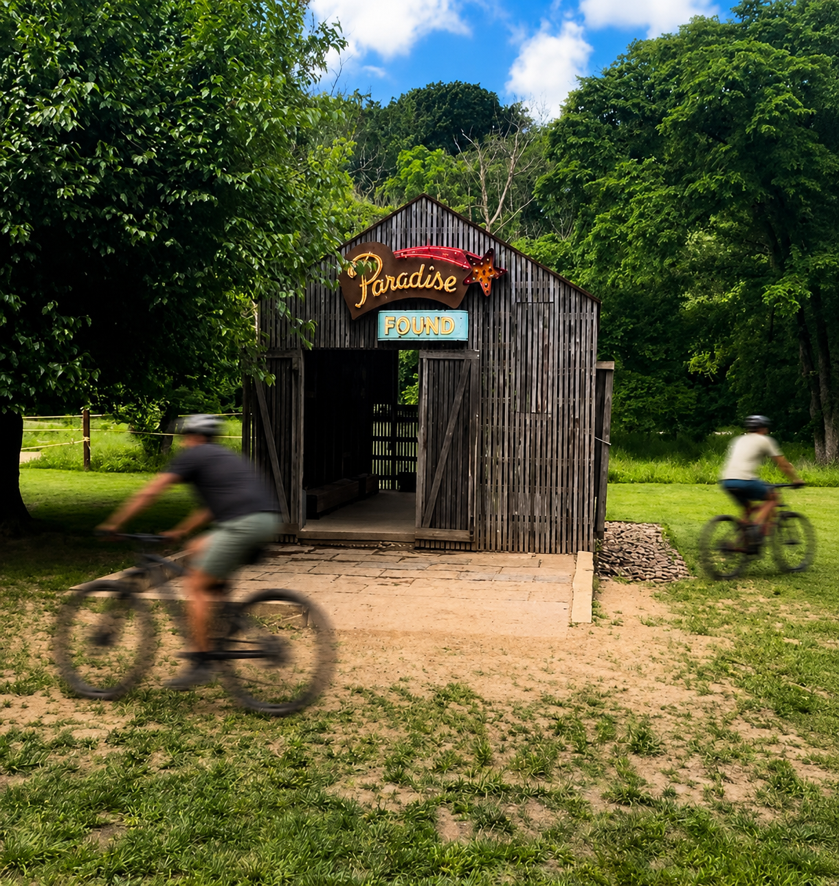 Paradise Found barn at Coler Preserve with cyclists moving through the landscape